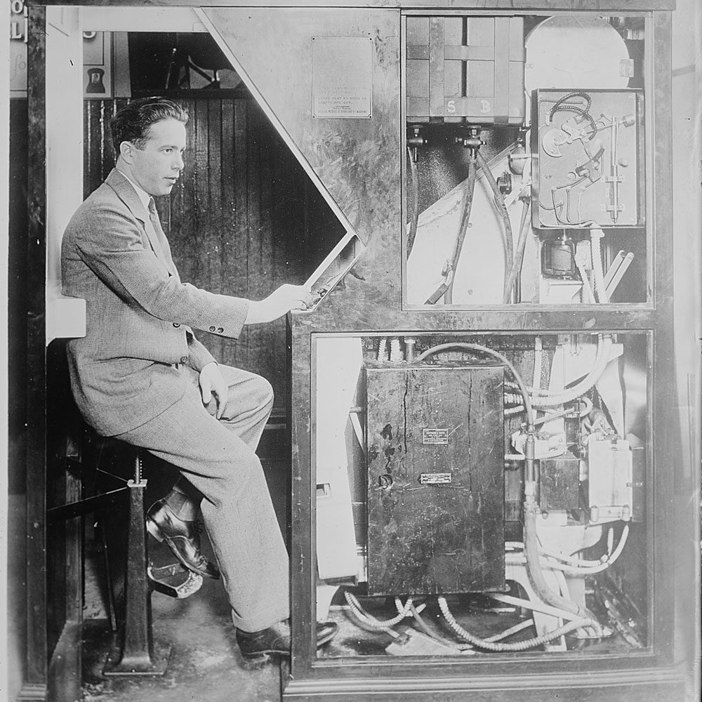 Anatol Josepho sits at the Photomaton photo booth he invented — eight photos for a quarter — which made its public debut in September 1925 in New York. Photo from Flickr Commons Project