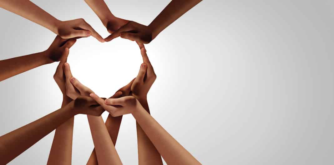 Group of linked hands from several people, forming a heart shape between them